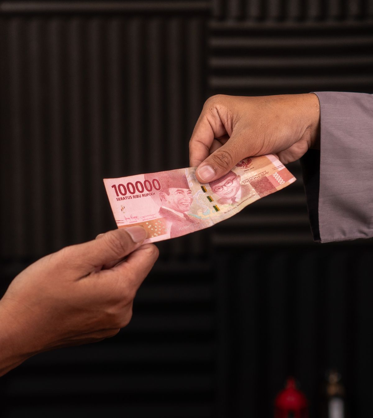 Dwie dłonie przekazujące sobie banknot nad ladą